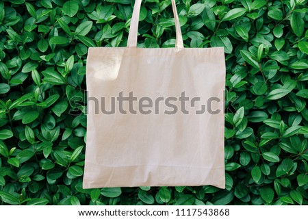 Blank White Mockup Linen Cotton Tote Bag on Green Bush Trees Foliage Background. Eco Nature Friendly Style. Environmental Conservation Recycling Concept. Template for Artwork Text. Japanese