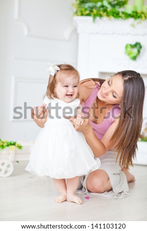 Happy mother and daughter taking the first steps on the warm floor