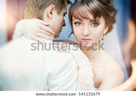 Portrait of a bride who is looking at us from behind the groom