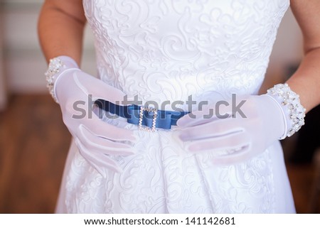 Bride in beautiful gloves, adjusts the strap on a white lace dress