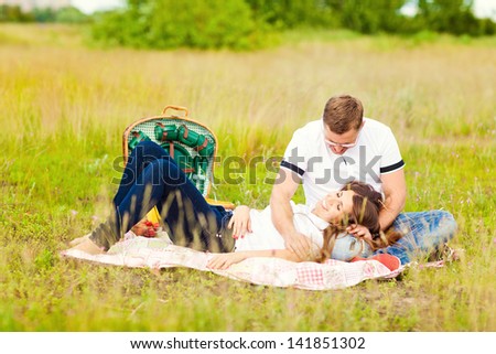 Happy couple with a dog having fun outdoors outside the city. Picnic outdoors in nature.