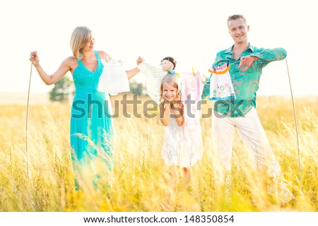 Happy family and a pregnant woman dry clothes of the child in the field. Cheerful family blonds. Fun in nature. Walk in the field.