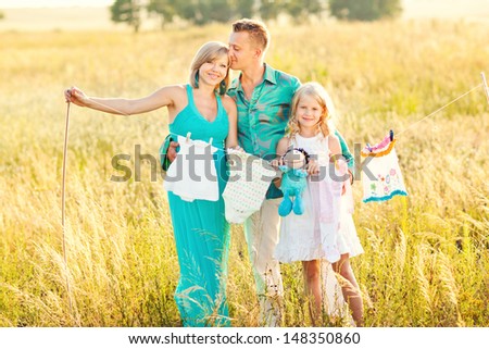 Happy family and a pregnant woman dry clothes of the child in the field. Cheerful family blonds. Fun in nature. Walk in the field.