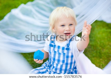 Baby boy playing  with cubes outdoors. The boy reaches out to her mother. Call for help.