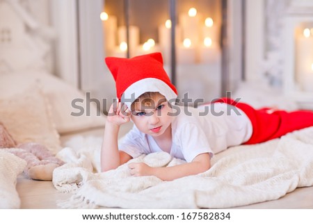 Beautiful sleepy boy waiting for Santa and went to sleep near the fireplace. Christmas Eve. Christmas decor.