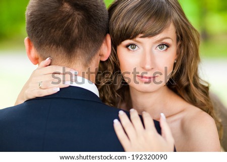 Beautiful girl looks out of a strong man's shoulder. Bride and groom. Encouragement and support. Relationships.
