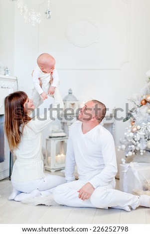 Photo of beautiful young family near the fireplace in design interiors. Christmas holidays.