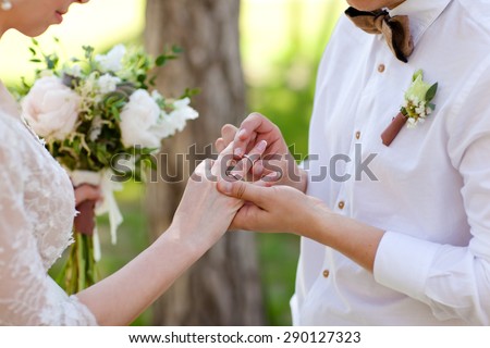 Hands with rings Groom putting golden ring on bride's finger during wedding ceremony