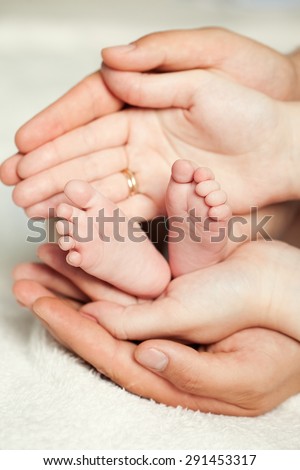 Mom and Dad hold baby legs. Taking care of a newborn.