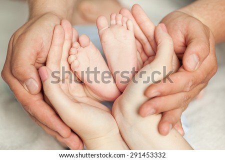 Mom and Dad hold baby legs. Taking care of a newborn.