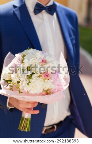 Bride and groom holding hands on a bouquet. Wedding rings. Wedding vows.