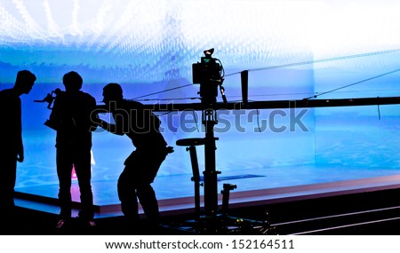 Silhouettes Of Film Crew In Front Of Blue Lighted Stage. Selective Focus.