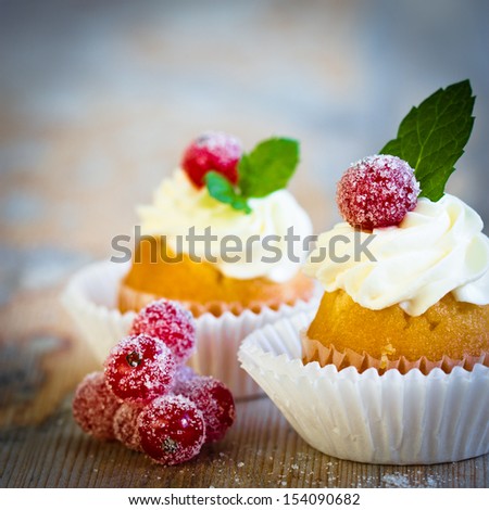mini cupcakes decorated with white frosting, sugared red currant and fresh mint leaves. Selective focus