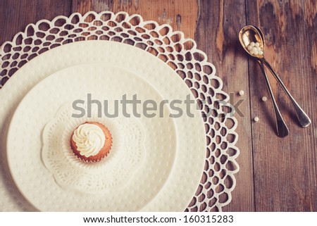 Beautiful tableware with little cupcake.  Selective focus on cupcake, top view.