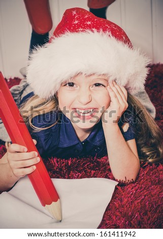 Happy little girl writing letter to Santa. Selective focus on face