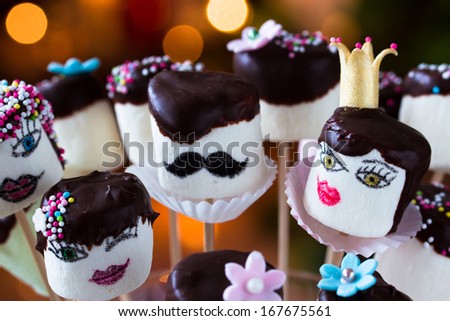 Funny marshmallow pops with hand-painted faces. Decorated with dark chocolate and sugar sprinkles. Selective focus