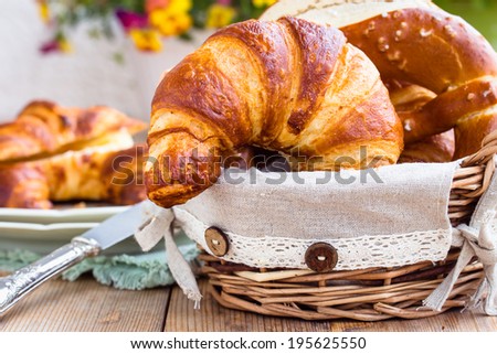 Fresh croissants and pretzels in basket for breakfast. Selective focus.