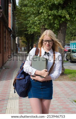 Blond school girl with nerd glasses on her way to school / home. Selective focus.