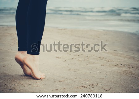 Close-up of gil\'s bare feet on cold wet sand. Toned image.