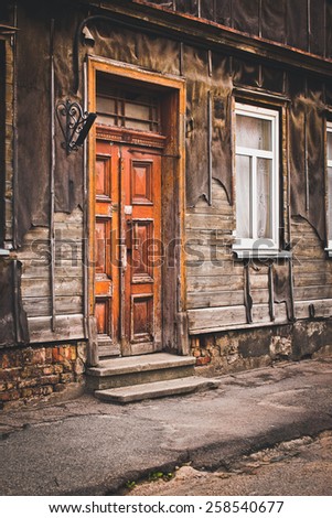 Entrance area of old wooden house. Door, steps, window and part of sidewalk. Selective focus.