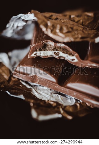Close-up of a chocolate bar missing one bite. There is a little heart shape on a white filling. Selective focus.