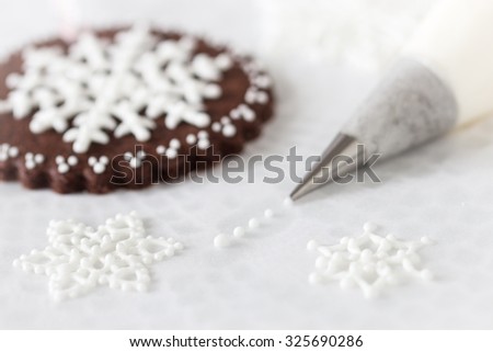Piping white snowflakes with royal icing, Selective focus.