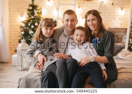 Christmas day.Young family gleefully congratulates each other Marry Christmas.On bed there are many Christmas gifts in bright packings and Christmas-tree decorations.Merry Christmas.Happy New Year