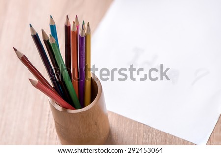 coloured pencil and paper note on wood table