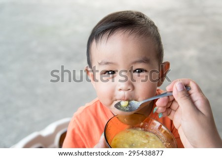 Little Asian baby eating rice porridge in smile