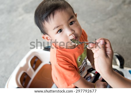 Little Asian baby boy eating rice porridge
