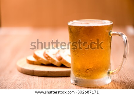beer in mug glass with bread on wood table