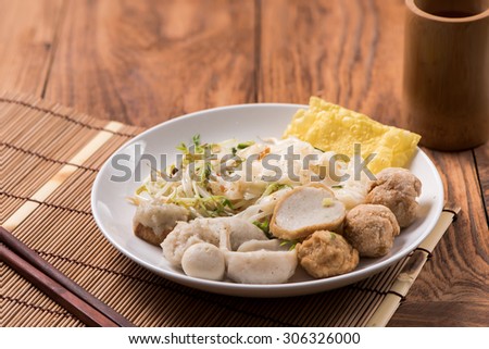 Wide rice noodles with vegetables, pork and tamarind sauce in Thai style on wood table