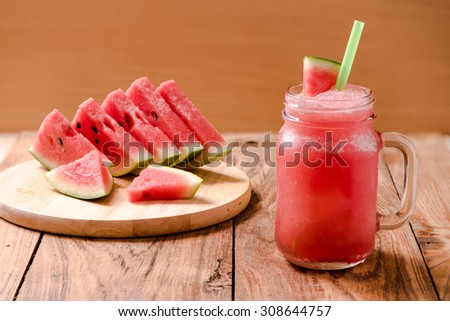 Closeup watermelon juice in glass on wood table with with slices of watermelon