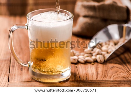 beer in mug glass pouring from top with bean on wood table