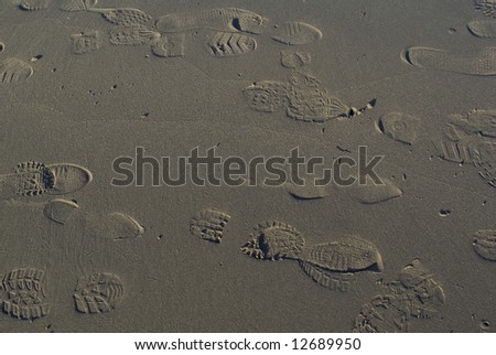 Footprints of different shoes and sneakers on beach sand
