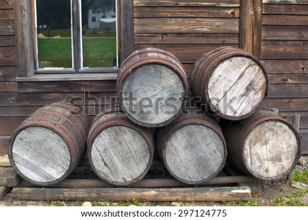 Wooden barrels piled up in front of Pioneer wood log cabin XIX century
