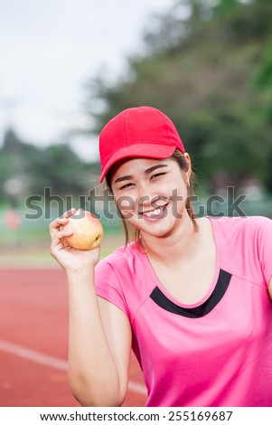 female runner  show apple on the running track and bottle of wat