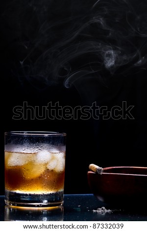 glass of whiskey with ice cube, cigar and smoke