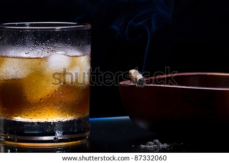 glass of whiskey with ice cube, cigar and smoke