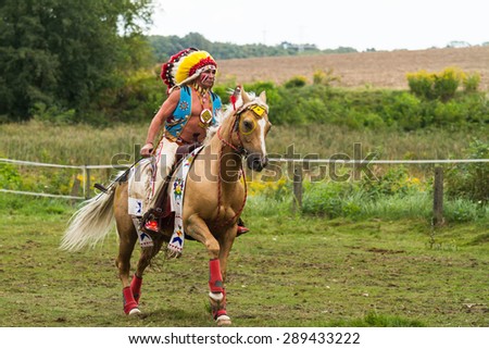 Barglowka, Poland - September 26, 2012: A man dressed as Indian chief with head-dress rides a horse during an event in Barglowka, Poland