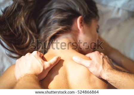 Couple and lovely moments in the bed - Close up of boyfriend giving massage for his beautiful girlfriend relaxing in a bed whit white sheets - Focus on hand