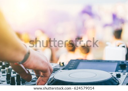 Close up of DJ\'s hand playing music at turntable on a beach party festival - Portrait of DJ mixer audio in a beach club above the crowd dancing and having fun - Party, summer, music and people concept