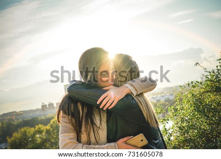 Happy meeting of two friends hugging at sunset outdoor - Pleasant moment of young sisters embracing in the wilderness as the sun shines upon them - Vignette editing