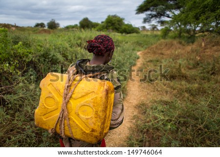 GAYO VILLAGE, ETHIOPIA - JUNE 19: Woman with a can of water from a nearby well (called Ella) on her way back to her village on June 19, 2012 in Gayo village, Ethiopia.