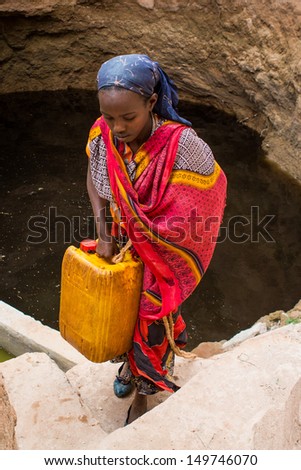GAYO VILLAGE, ETHIOPIA - JUNE 19: Woman with a can of water from a well (called Ella) on her way back to her village on June 19, 2012 in Gayo village, Ethiopia.