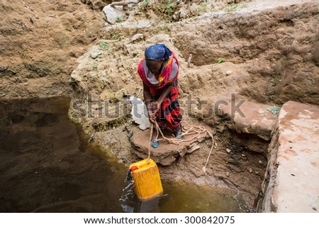 GAYO VILLAGE, ETHIOPIA - JUNE 19: Woman takes water from a well before returning to her village. The water is purified with tablets before drinking on June 19, 2012 in Gayo village, Ethiopia.