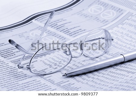 economic newspaper with glasses and pen
