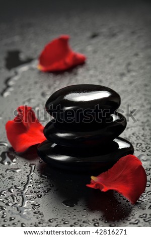 spa stones and rose petals over black background