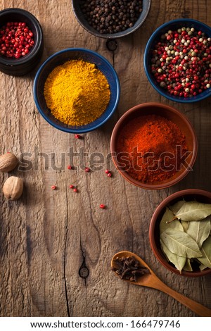 spices in bowls: pink and black pepper, paprika powder, curry, bay leaf