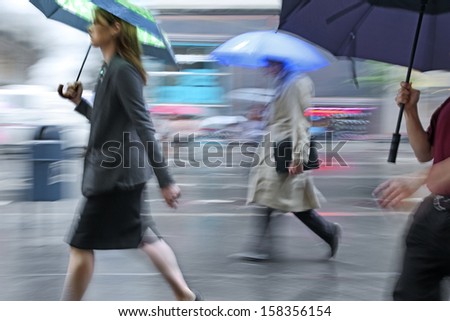 business people walking in the street on a rainy day motion blurred
